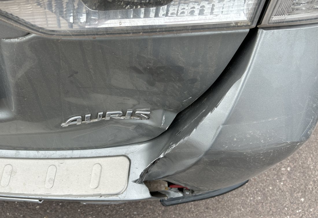 Aufgerissener hinterer Stoßfänger und verzogene Seitenwand eines silbernen Toyota Auris Kombi, wirtschaftlicher Totalschaden